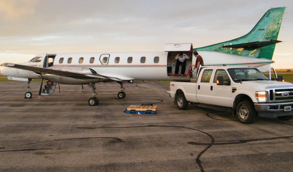 Charter Solutions staff unloading baggage from white pick-up truck onto aircraft